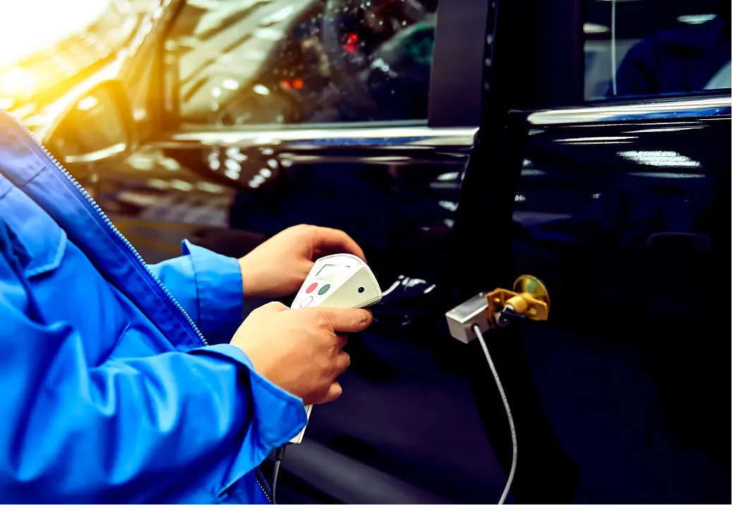 Person testing car with electronic device.