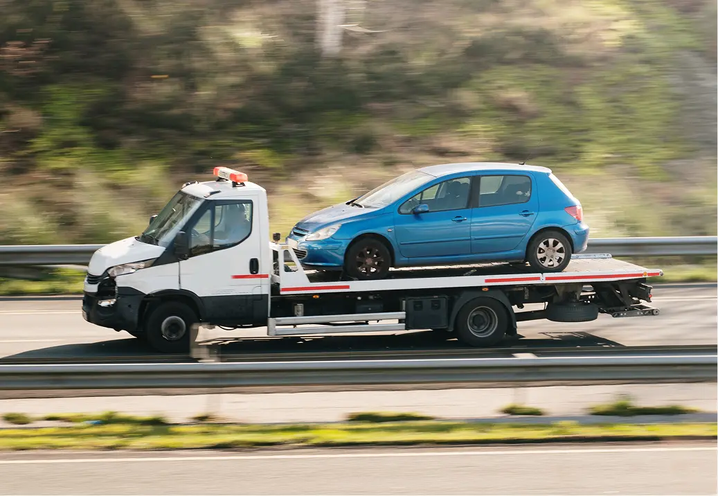 Tow truck transporting a blue car.