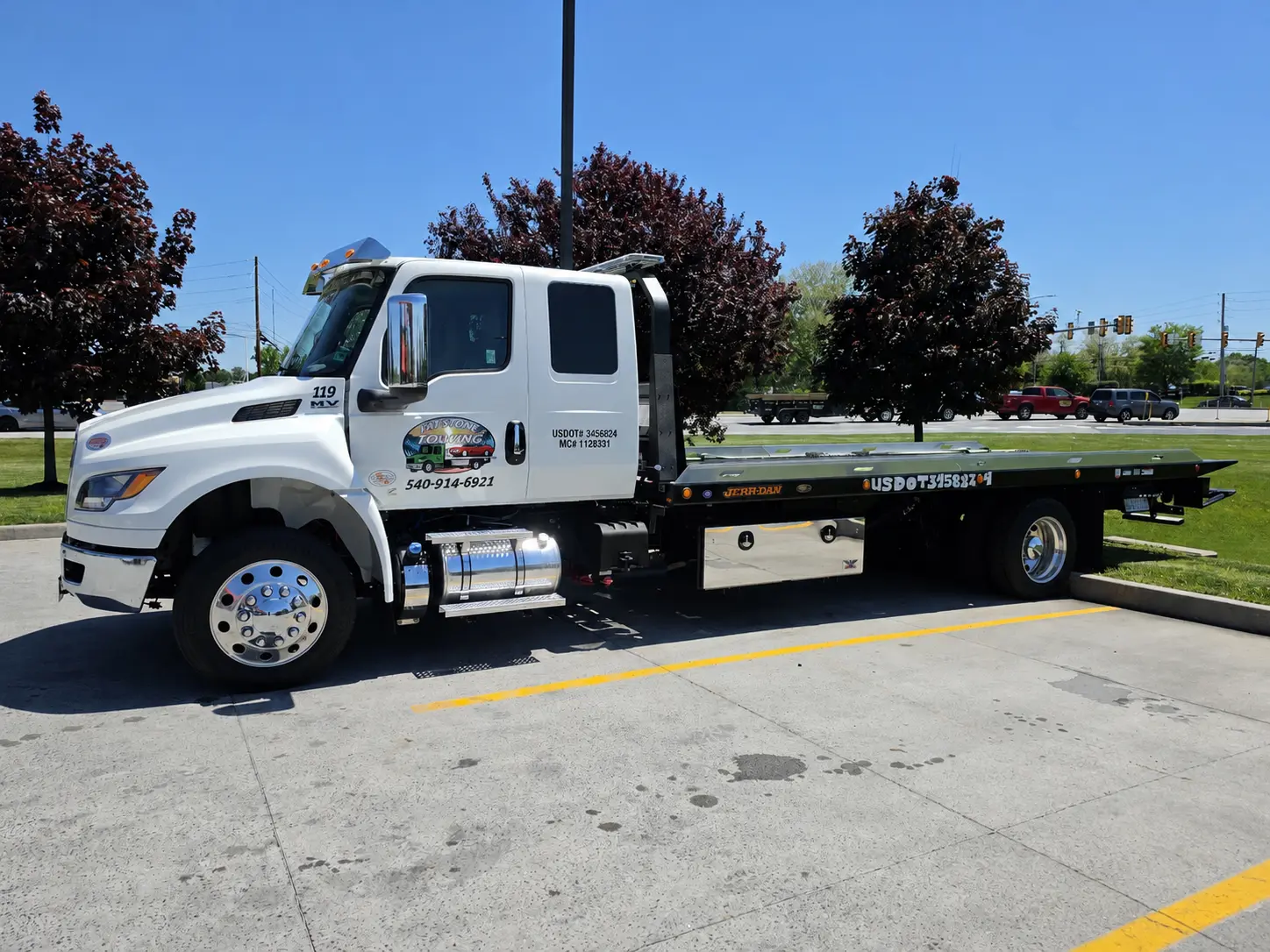 White tow truck parked in a lot.