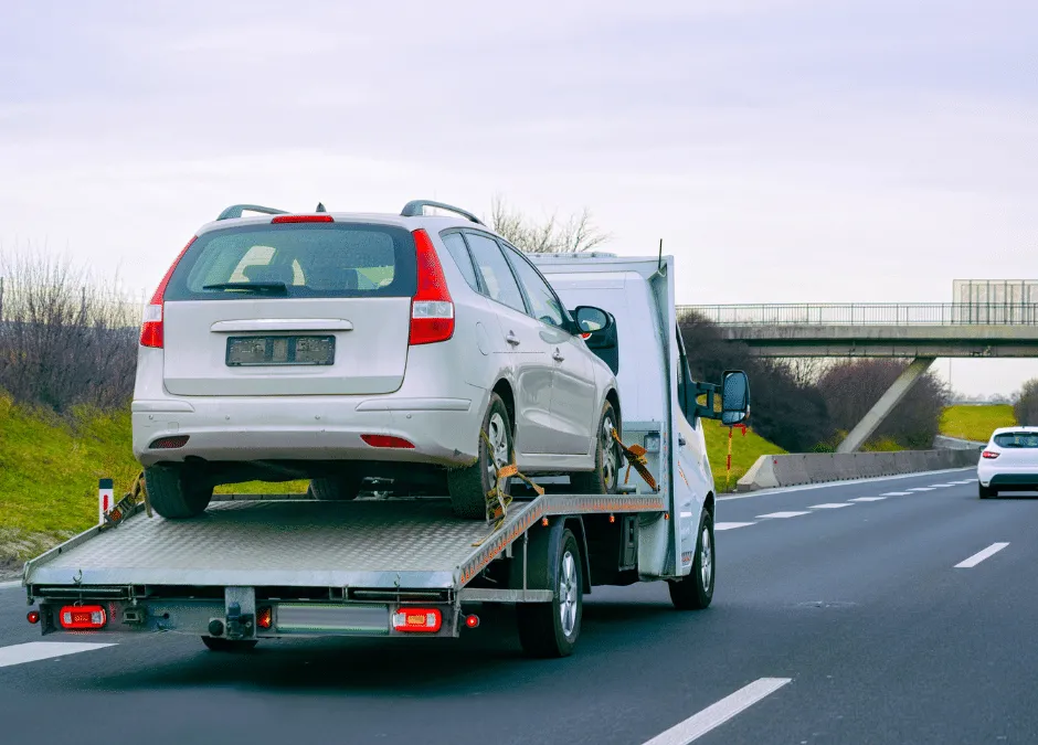 Tow truck carrying white car on highway
